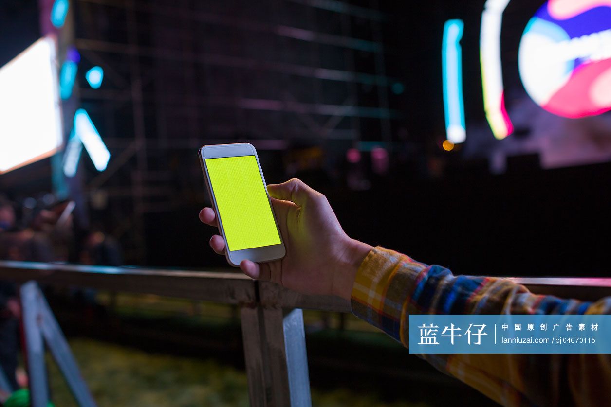 年轻男子在音乐节上使用手机