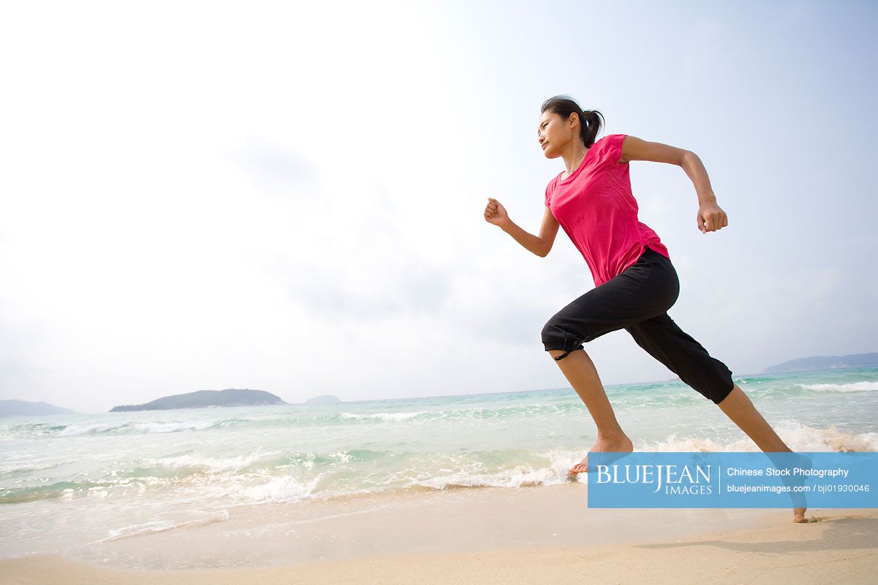 Young Chinese woman running on the beach