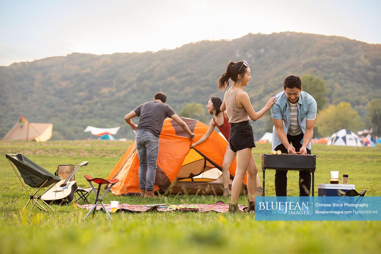 Happy young Chinese friends barbecuing outdoors