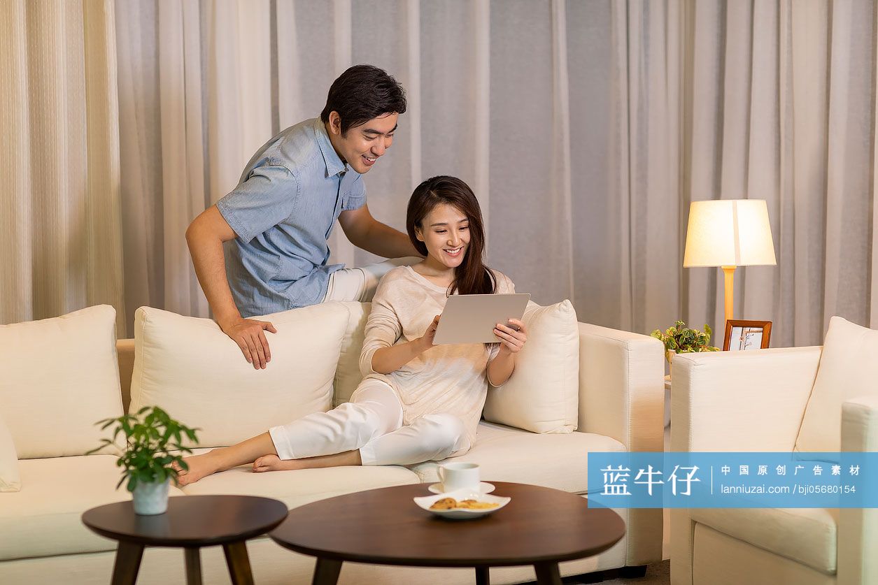 快乐的年轻情侣在客厅使用平板电脑-蓝牛仔影像-中国原创广告影像素材