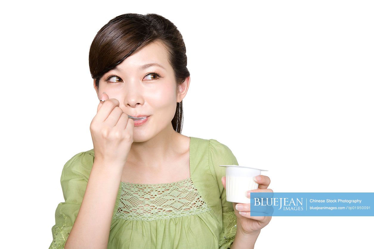 Portrait of young Chinese woman eating yogurt