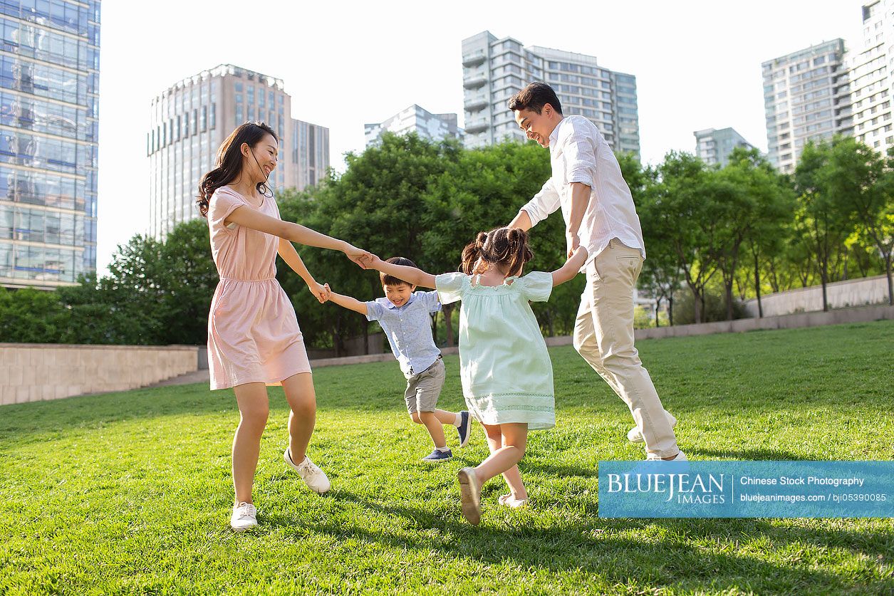 Happy young Chinese family playing in park