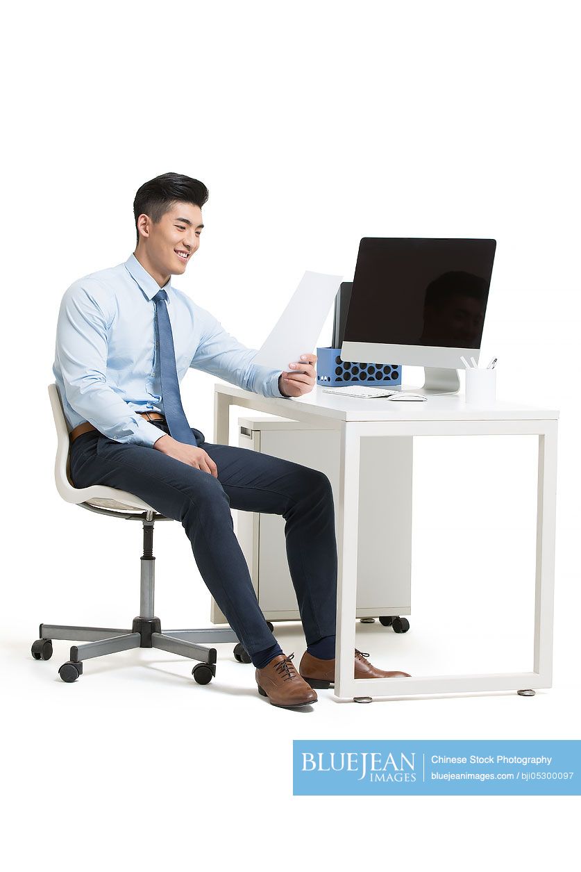 Young Chinese businessman reading files in office