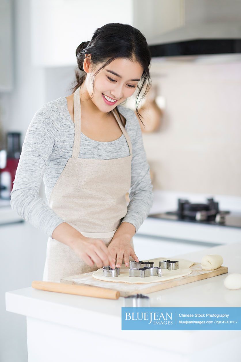 Young Chinese woman making cookies in kitchen