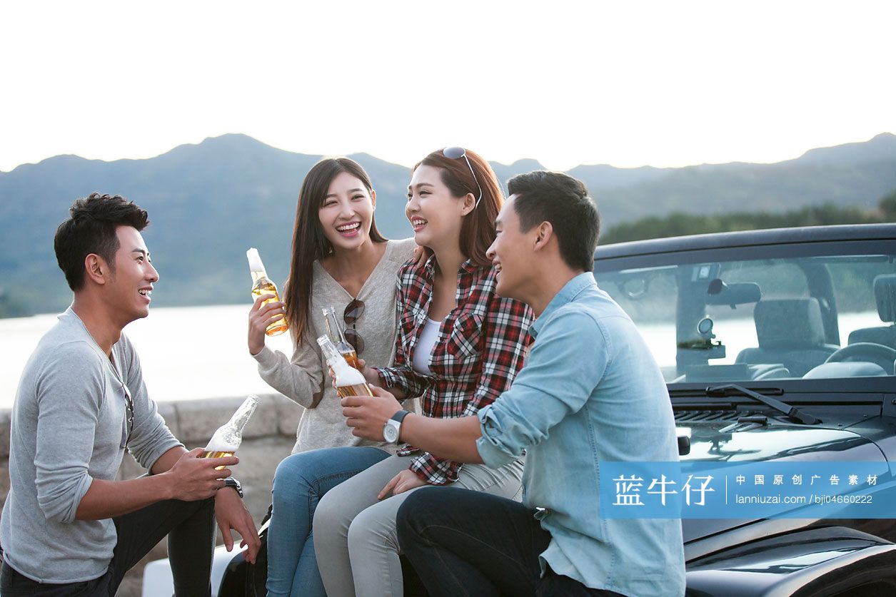 年轻人在吉普车旁喝啤酒