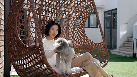 Happy young Chinese woman with pet dog on hanging-chair,4K