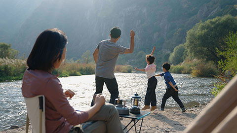 Happy young Chinese family camping outdoors