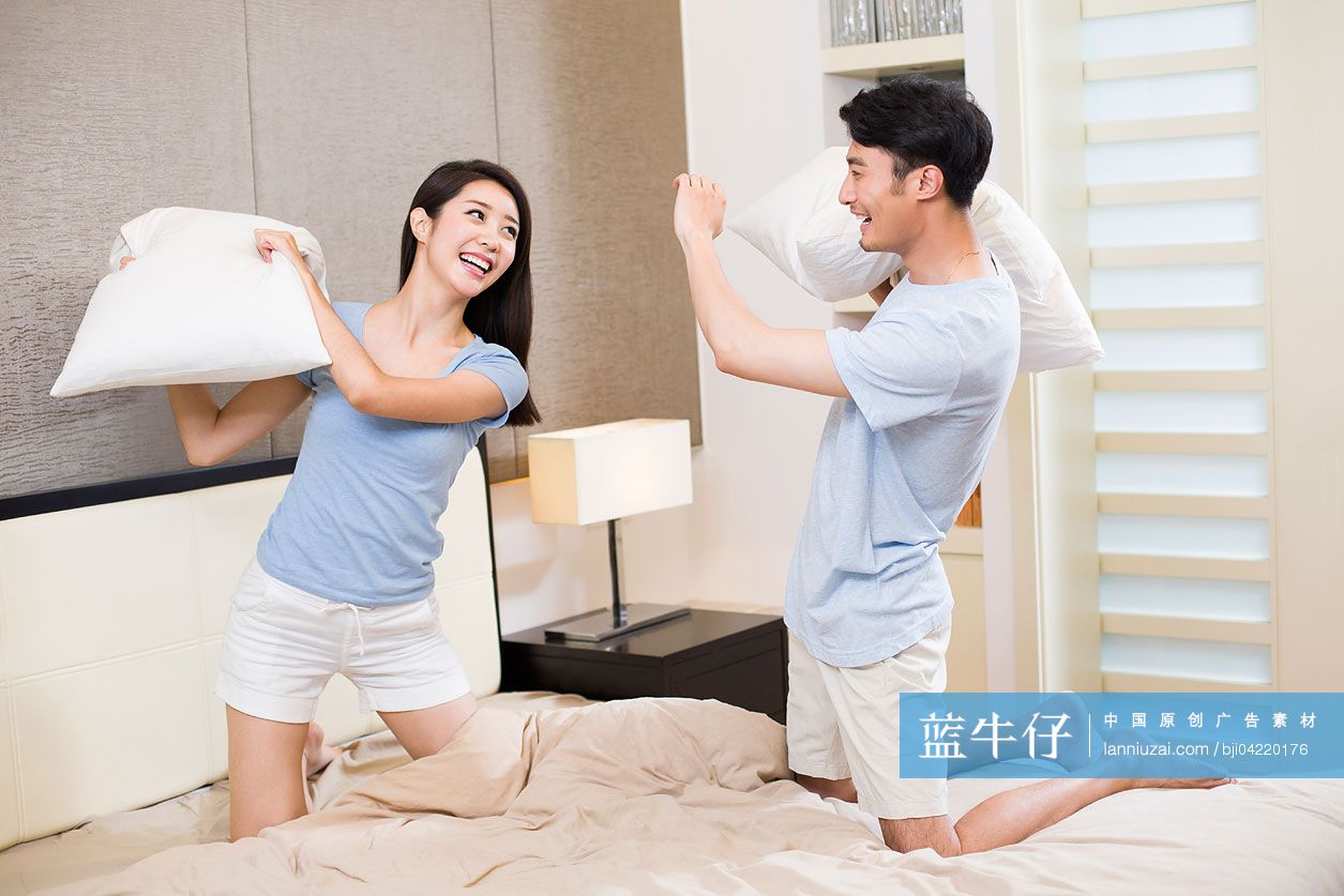 年轻夫妇在卧室打枕头仗