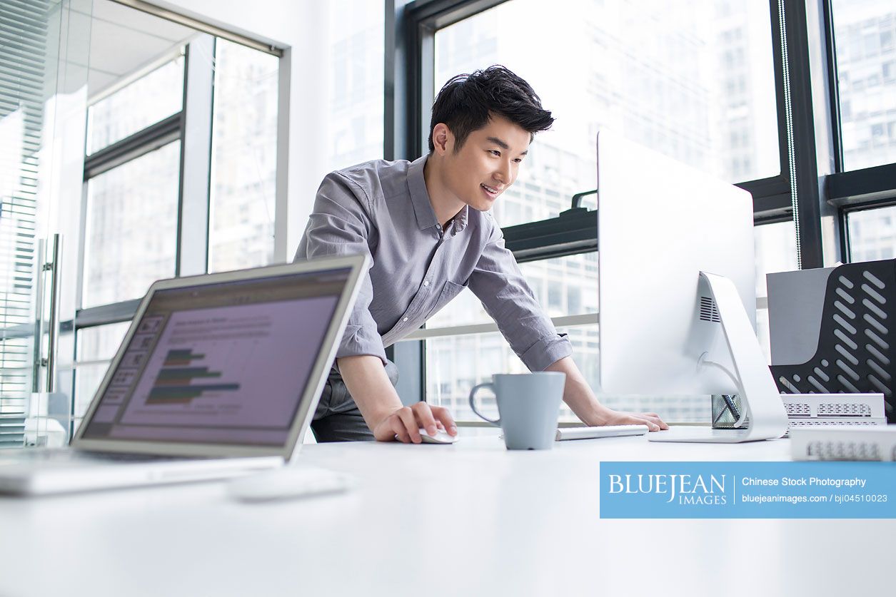 Young Chinese businessman using computer in office