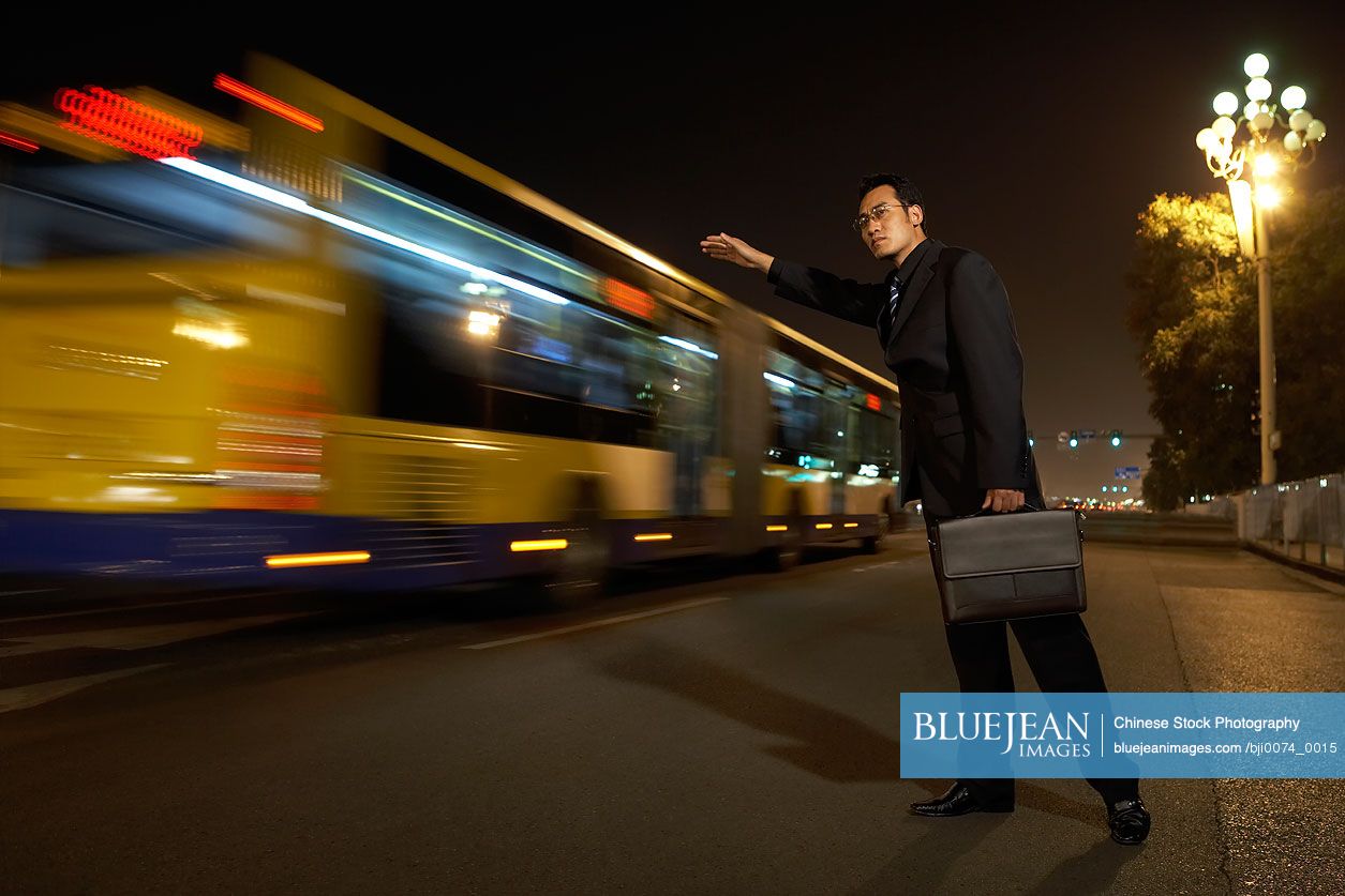 Chinese businessman hailing bus at night