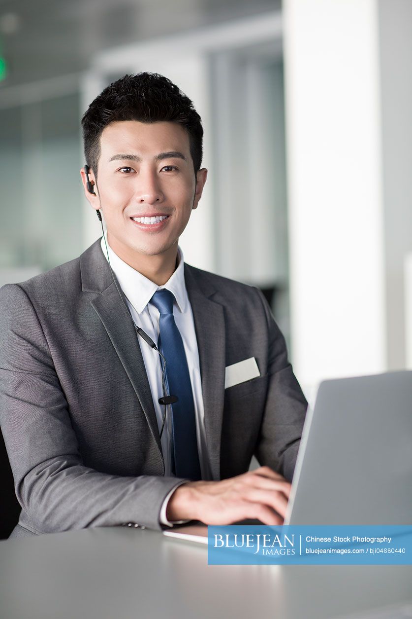 Young Chinese businessman using laptop