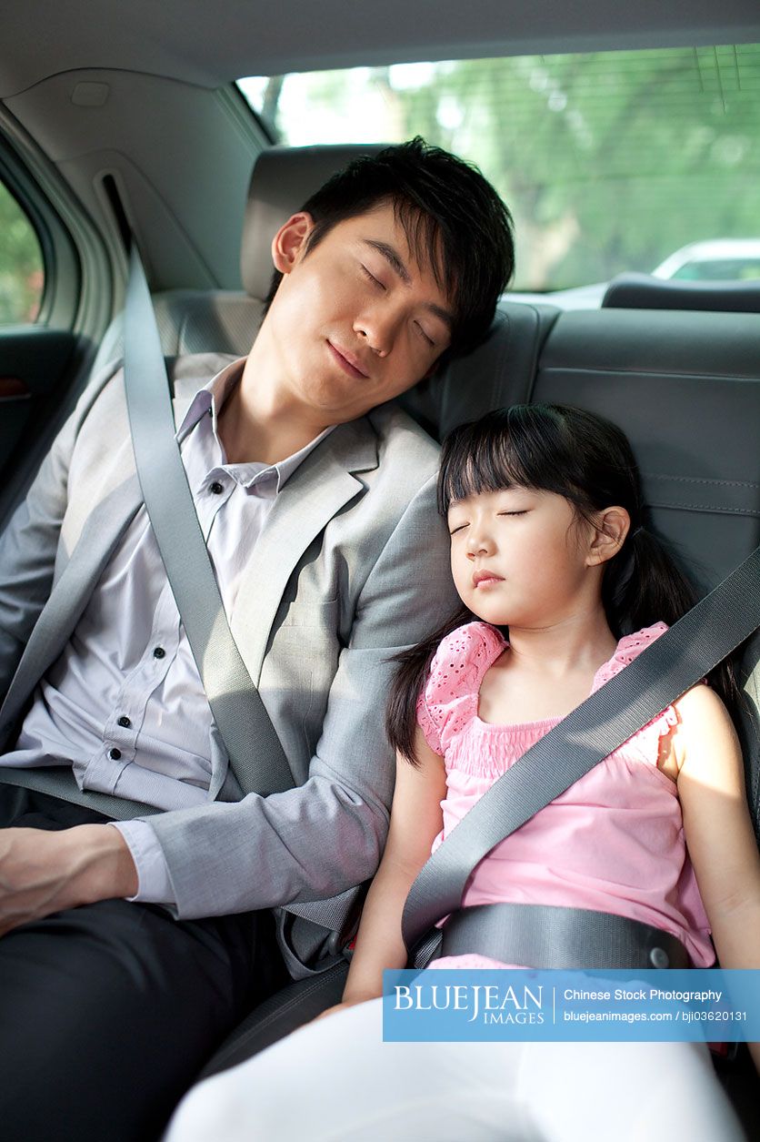 Chinese father and daughter sleeping soundly in car back seat