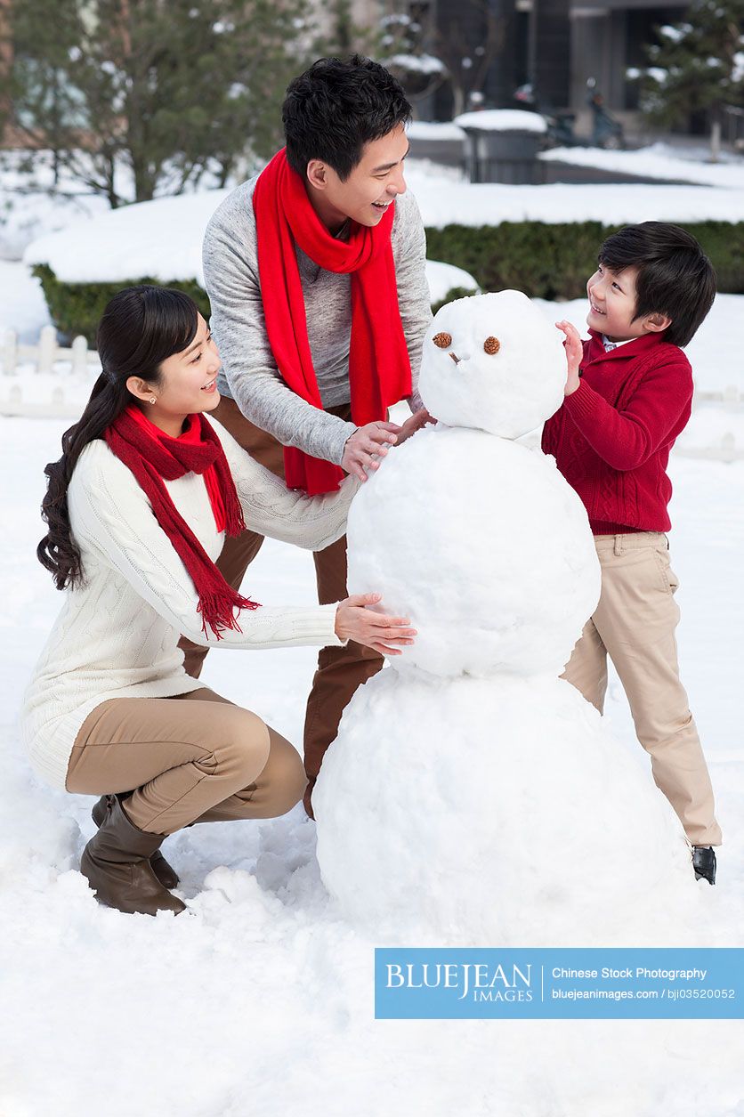 Happy Chinese family building snowman