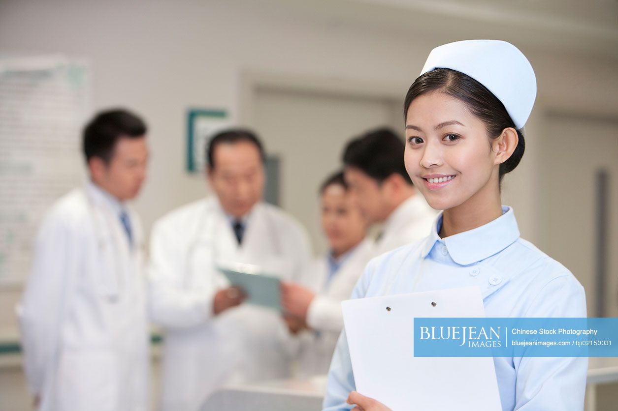Portrait of a confident Chinese nurse standing in front of her colleagues