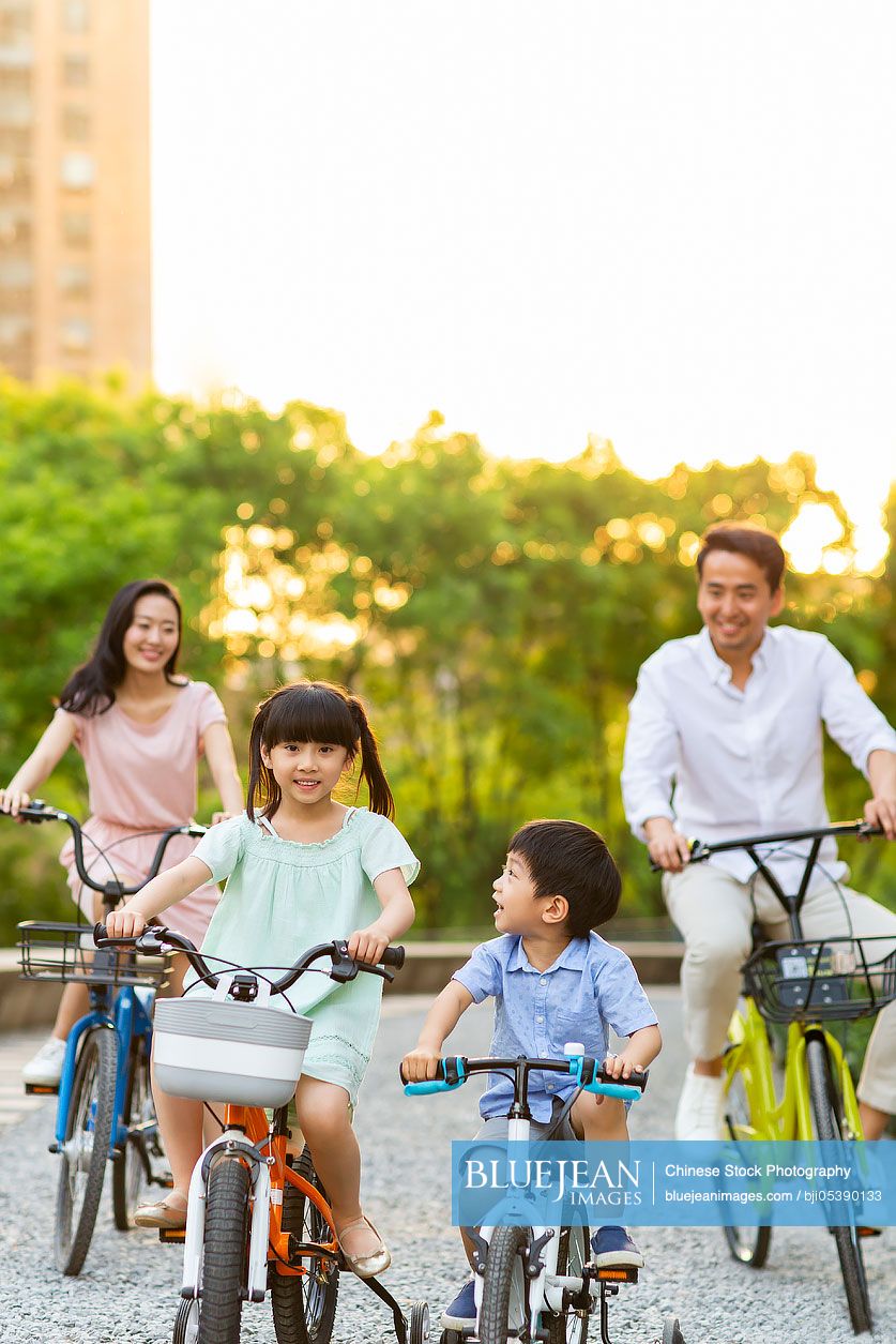 Happy young Chinese family riding bikes