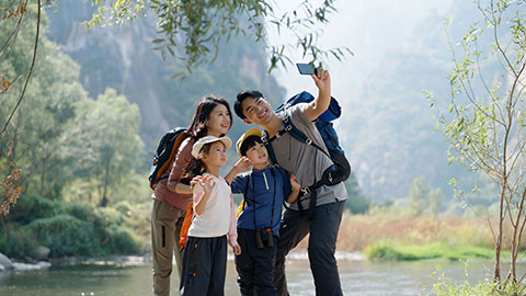 Happy young Chinese family hiking outdoors