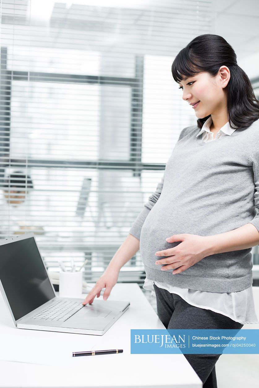 Pregnant Chinese businesswoman using laptop