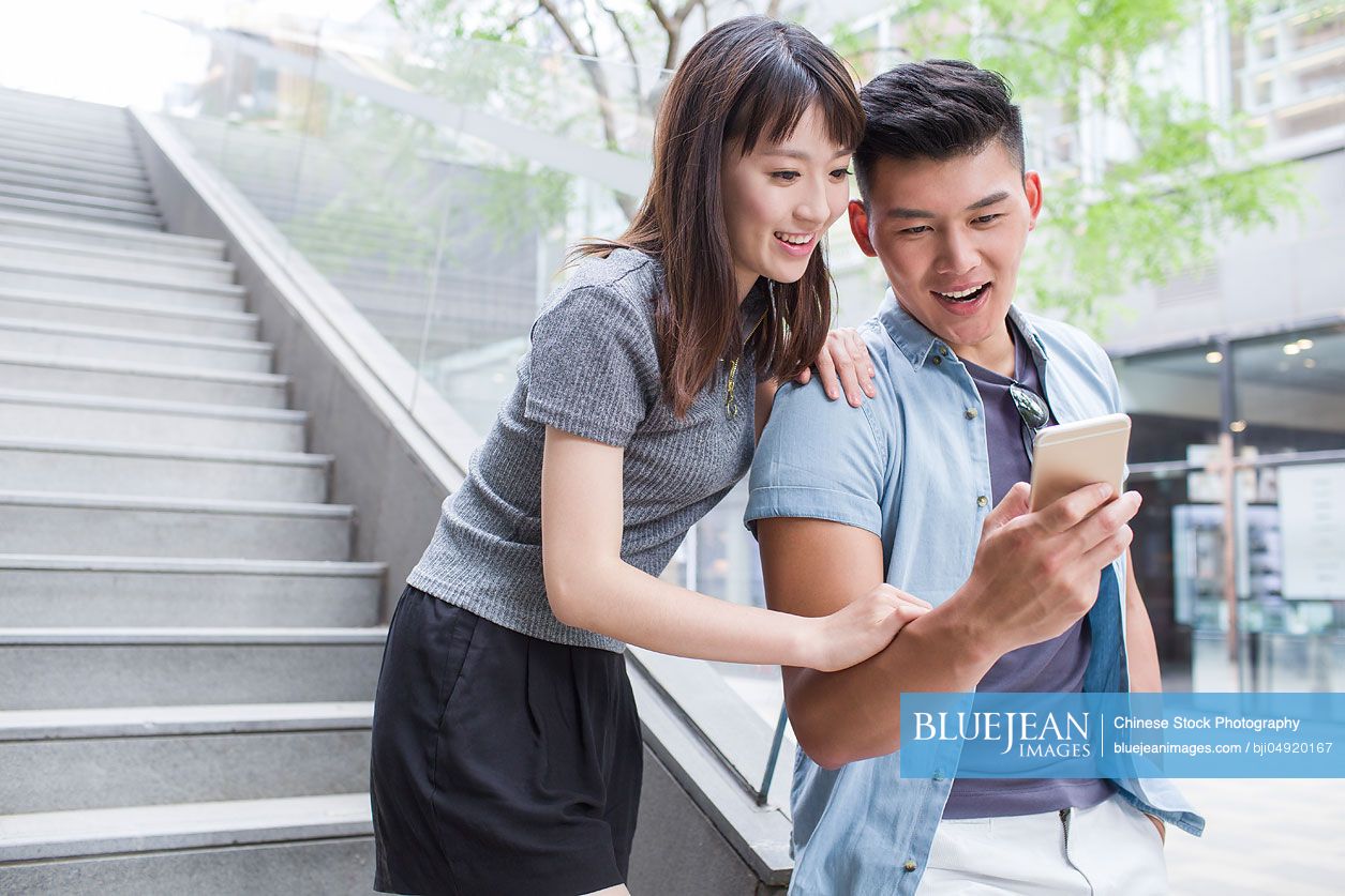 Young Chinese couple looking at a smart phone