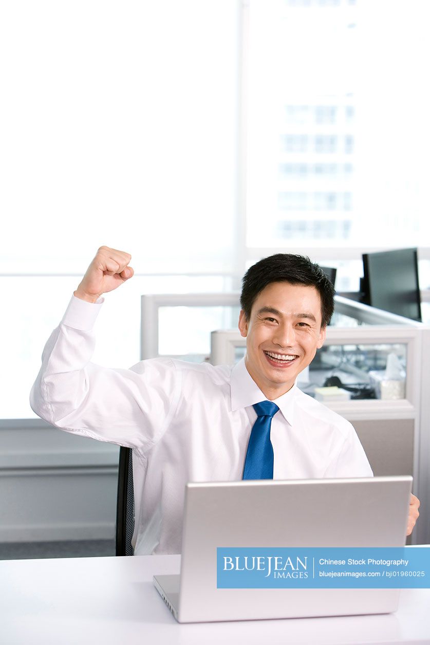 Happy Chinese office worker at his desk
