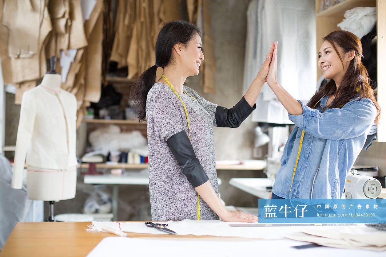 两个女服装设计师在工作室击掌庆祝