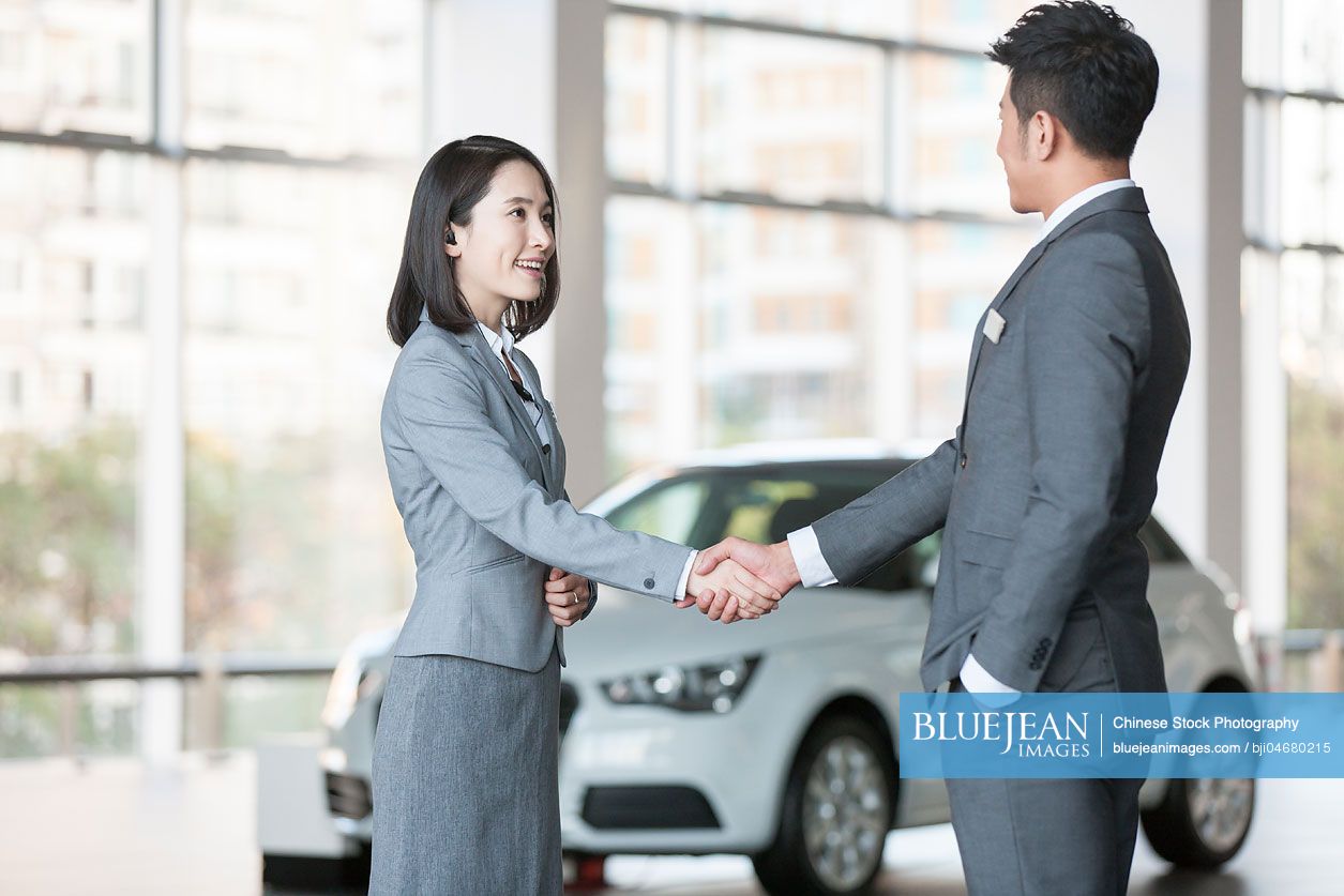 Chinese car saleswoman talking with customer