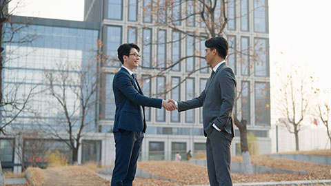 Confident Chinese businessmen shaking hands outdoors
