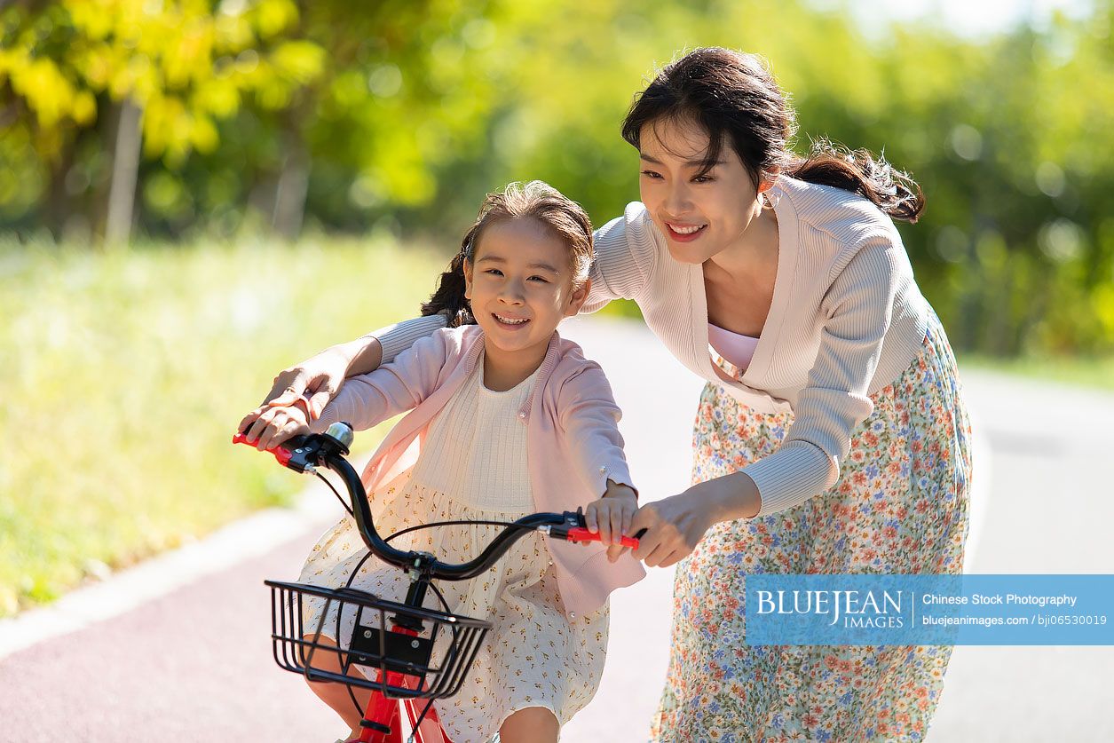 Chinese mother teaching daughter to ride bike