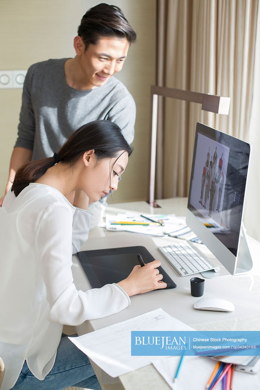 Young Chinese couple designing clothing together