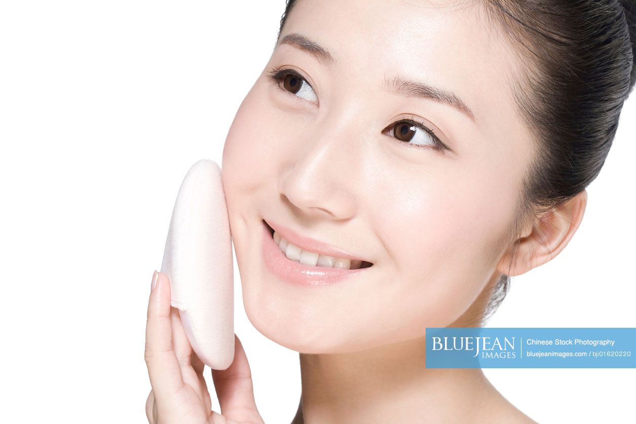 Beauty shot of a young Chinese woman holding a powder puff