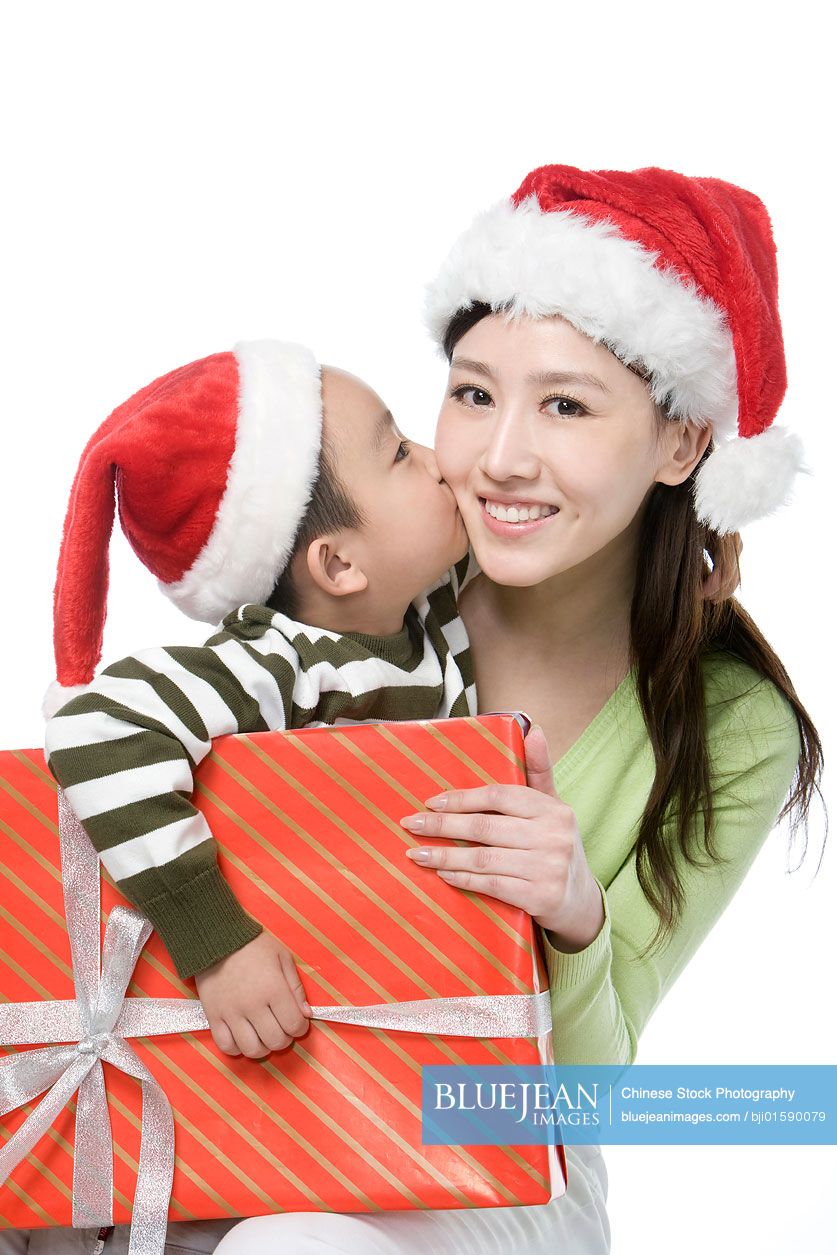 Chinese Mother and son with Santa hats holding gift box