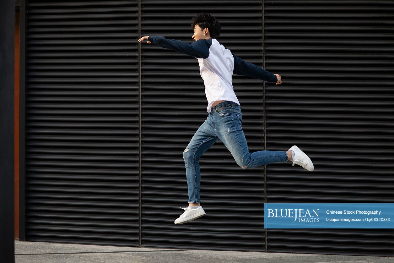 Happy young Chinese man jumping in the air