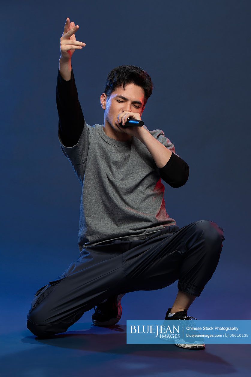 Studio shot of fashionable young Chinese man singing