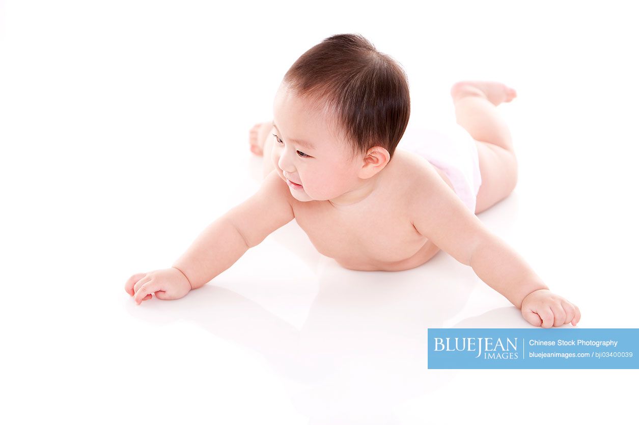 Studio shot of cute Chinese baby lying on floor