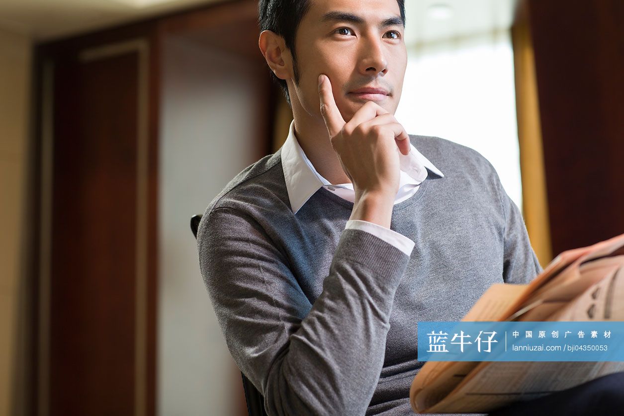年轻商务男士在书房看报纸