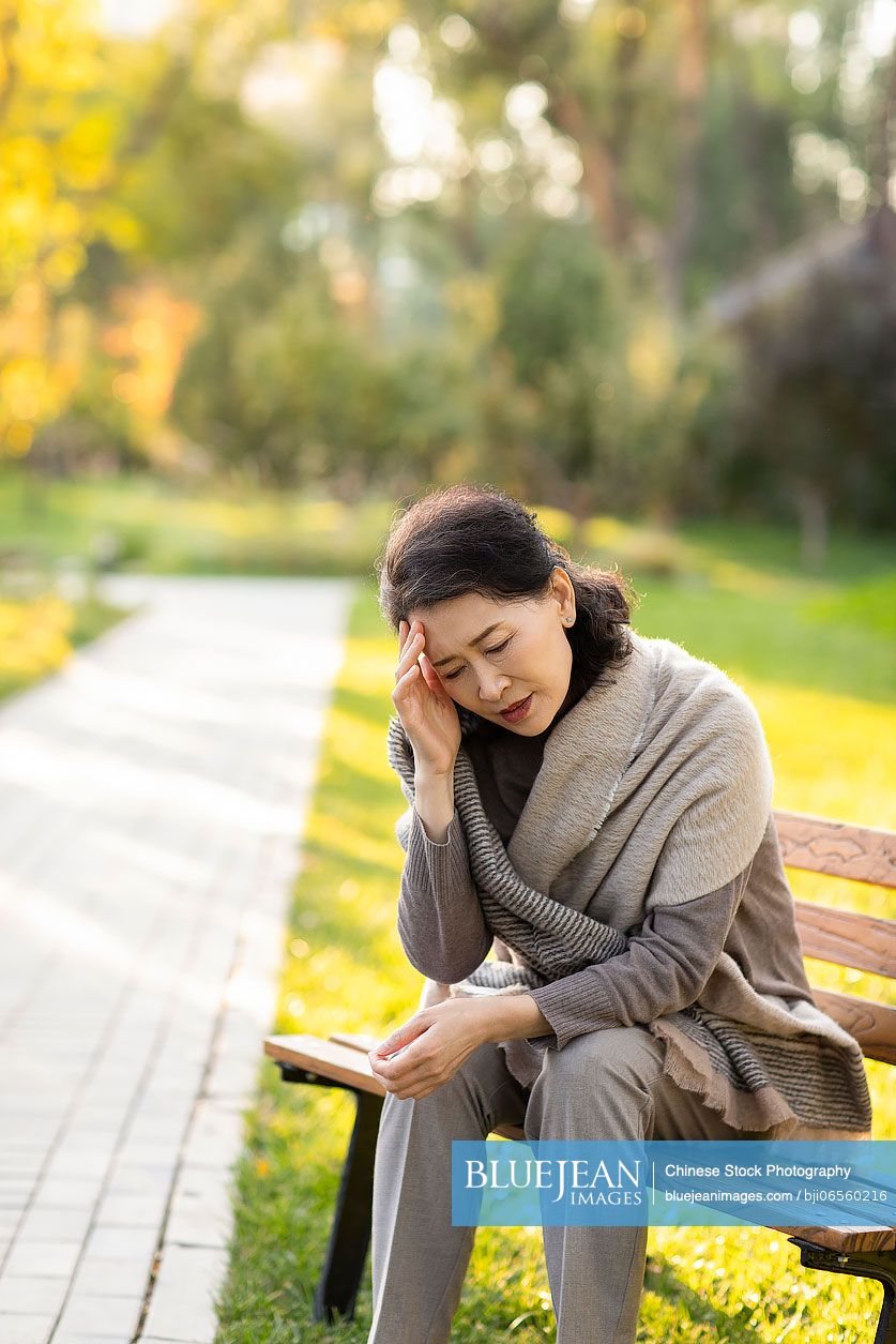 Senior Chinese woman sitting on park bench