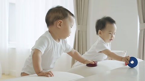 Two twin babies playing with building blocks