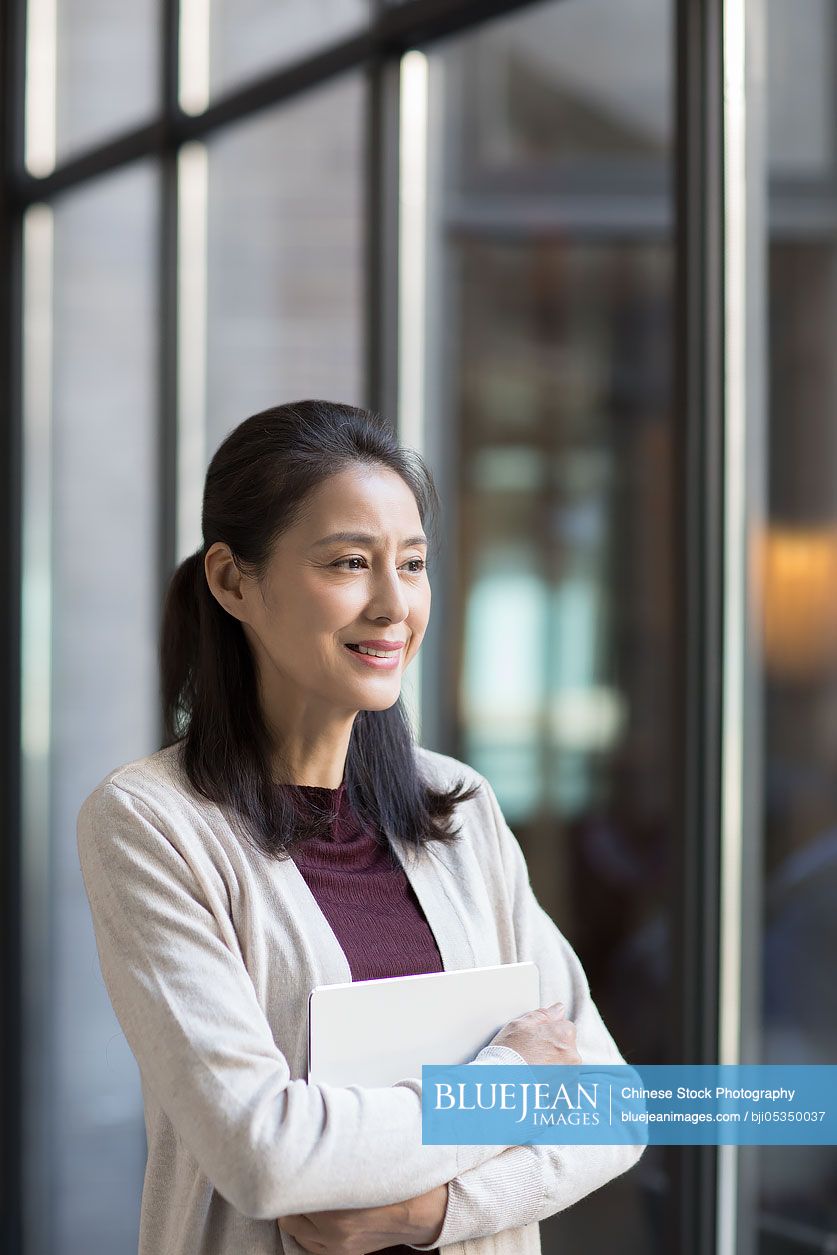 Elegant mature Chinese woman holding a digital tablet