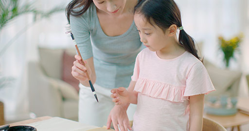 Happy Chinese mother and daughter writing calligraphy at home,4K