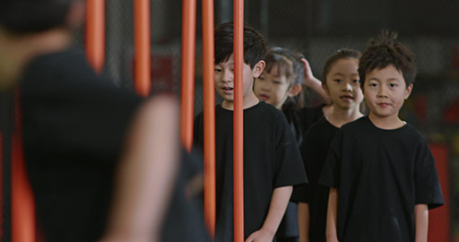 Active Chinese children having exercise class with their coach in gym,4K