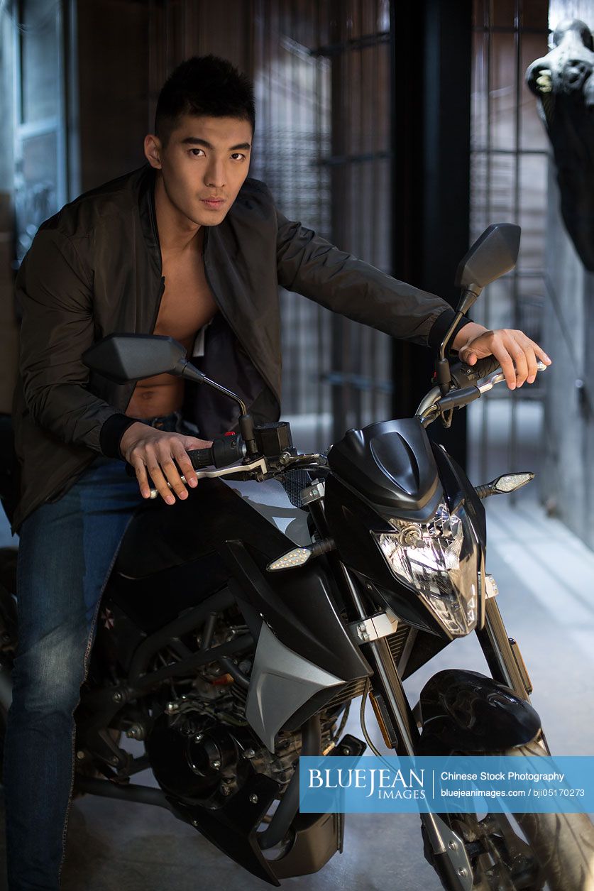 Young Chinese muscular man riding motorcycle