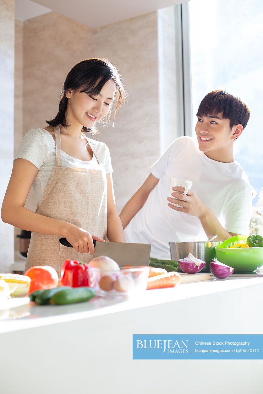 Happy young Chinese couple cooking in kitchen