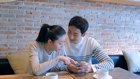 年轻情侣在咖啡店使用手机