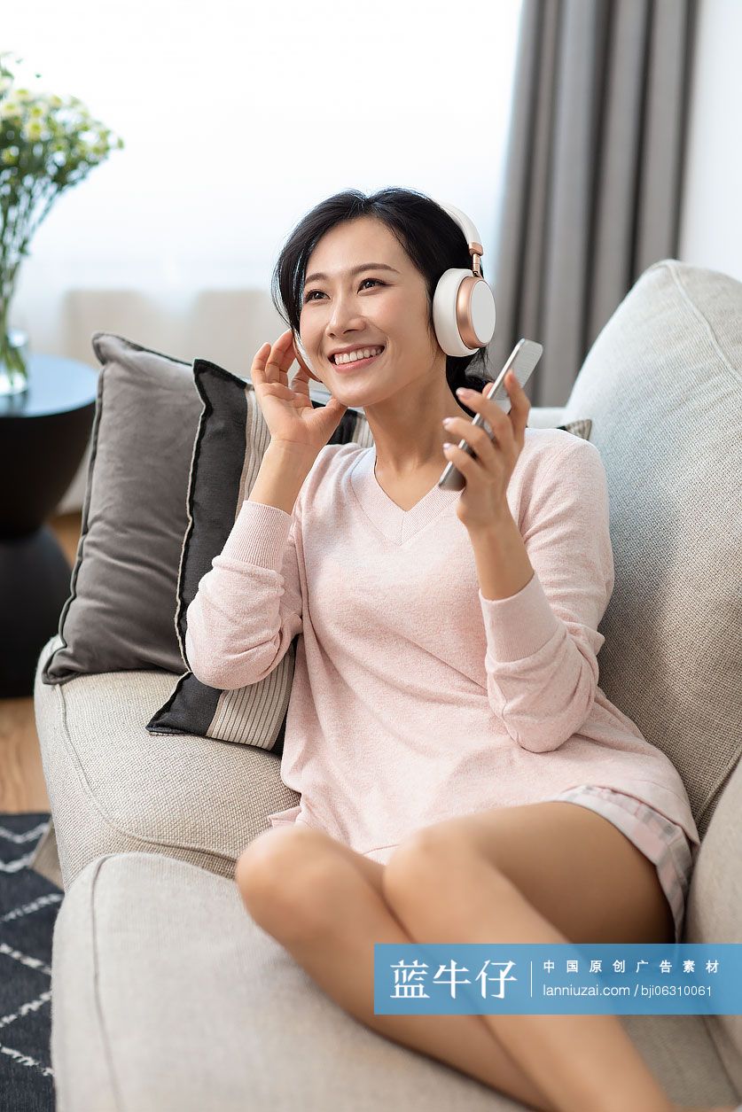 快乐年轻女士在家戴着耳机听音乐