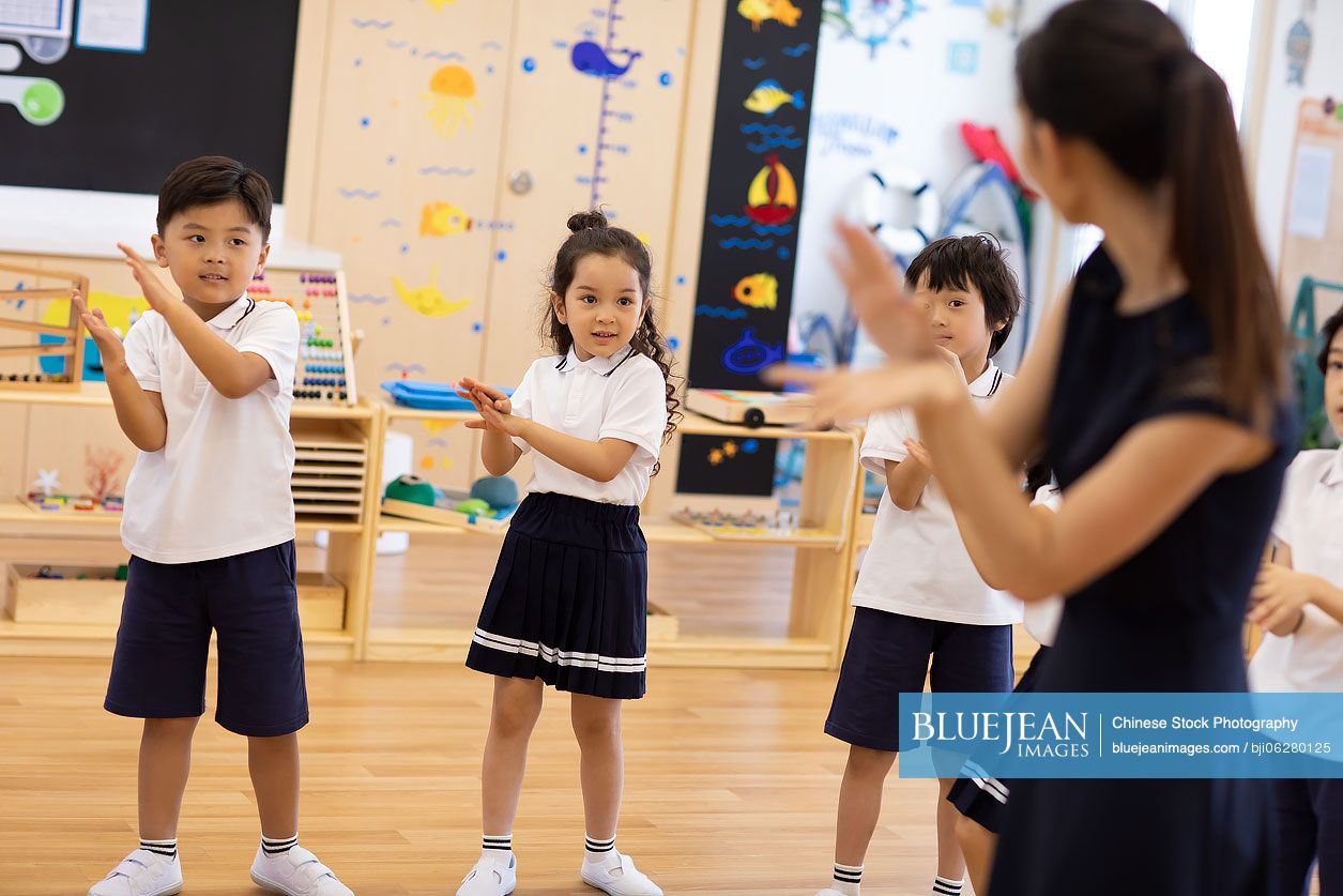 Chinese teacher teaching children dancing in classroom