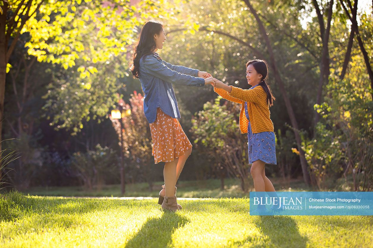 Happy Chinese mother and daughter having fun in park