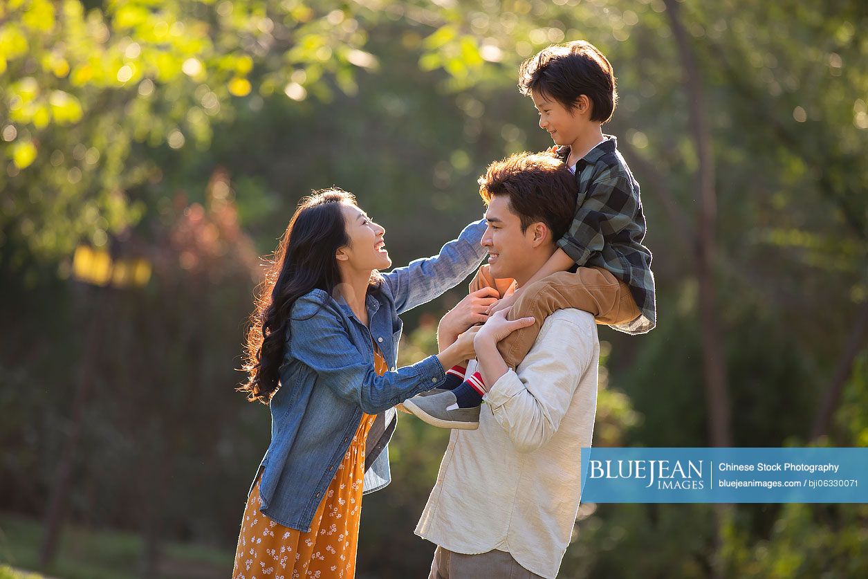 Happy young Chinese family having fun in park