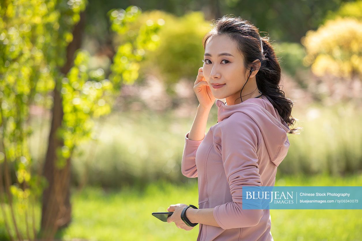 Young Chinese woman listening to music with earbuds