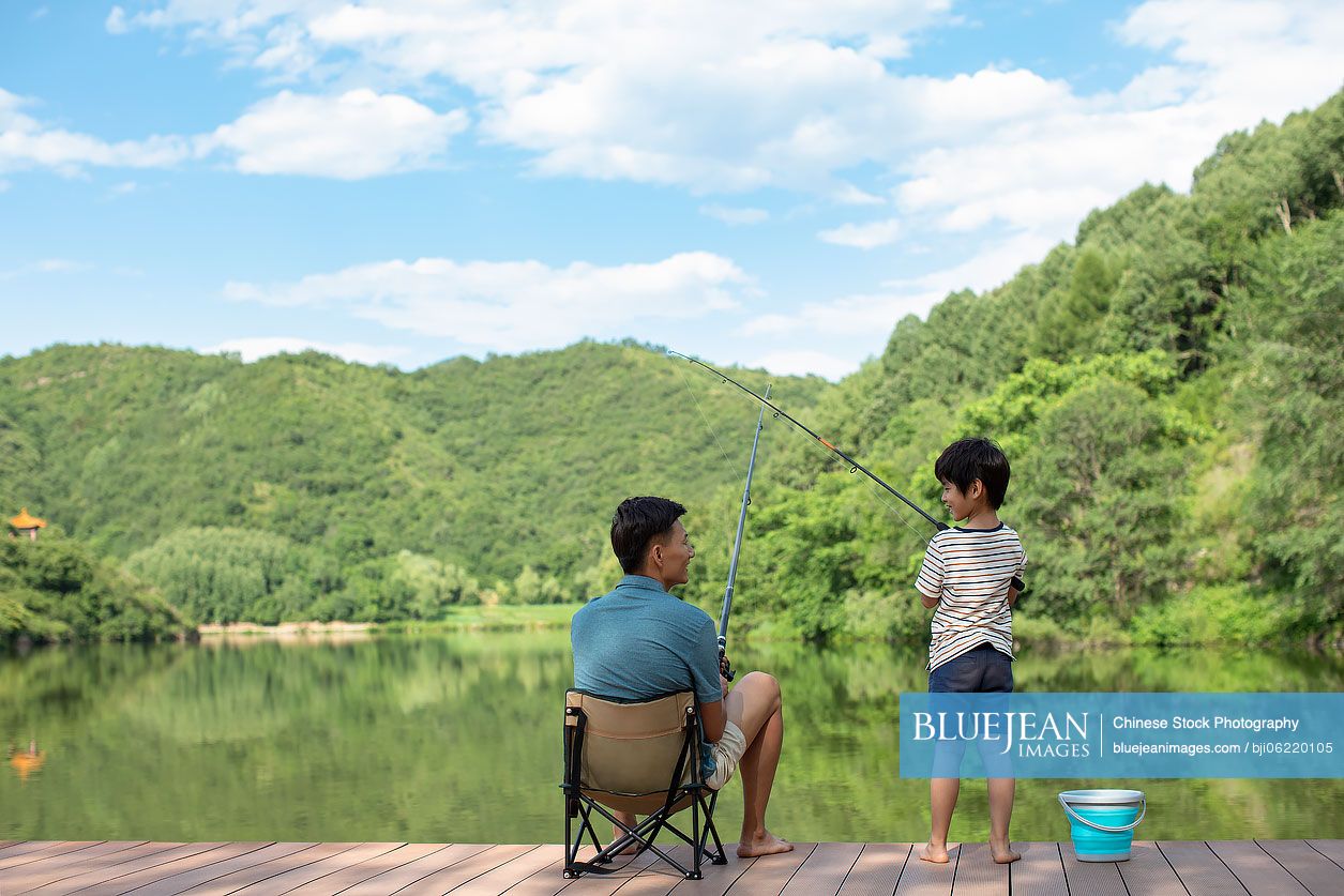 Happy Chinese father and son fishing by the river