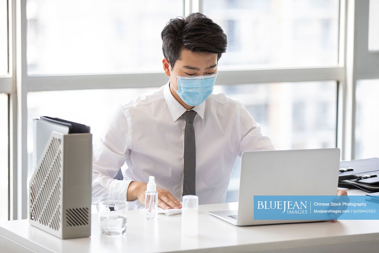 Young Chinese businessman using disinfectant in office