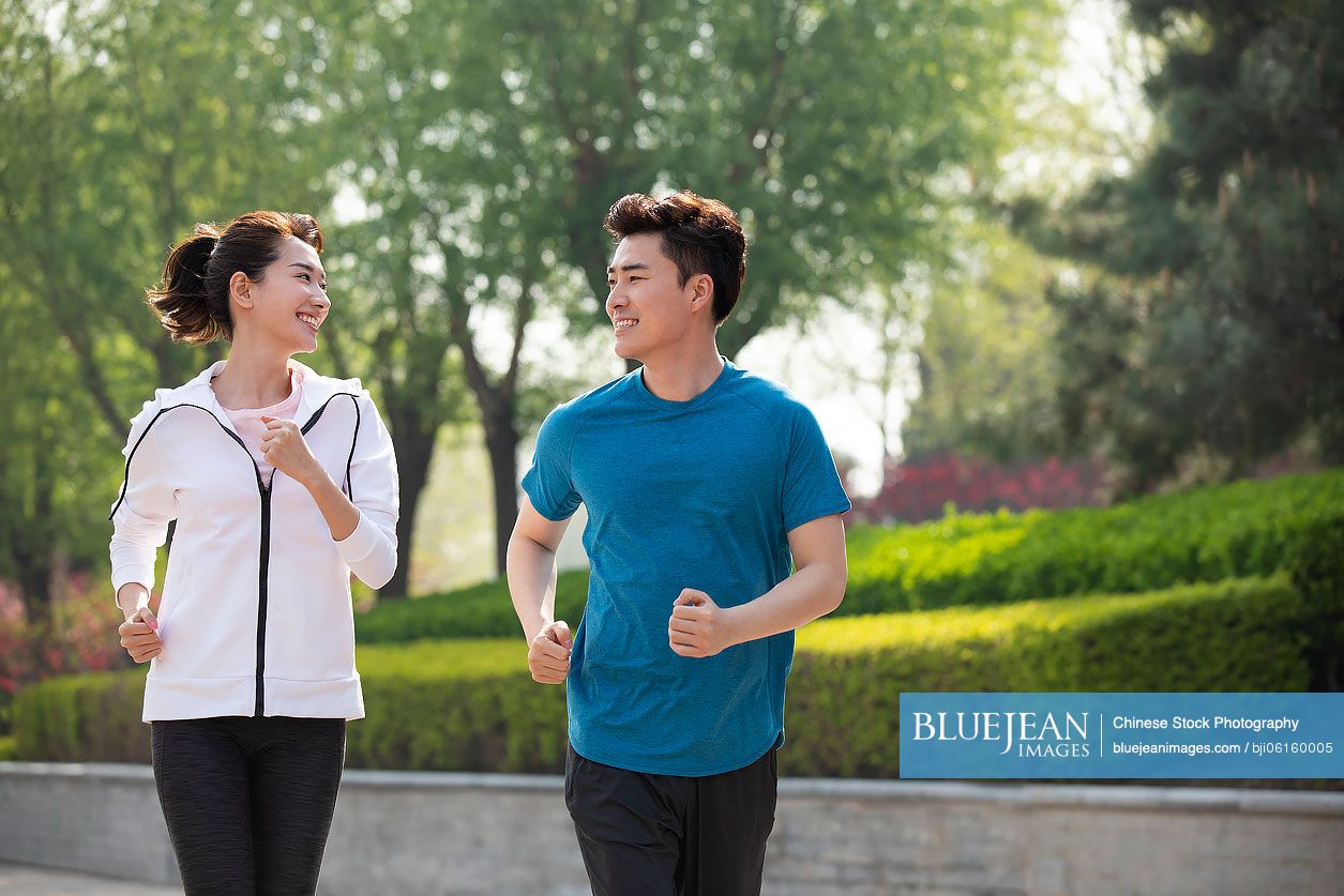 Happy young Chinese couple running in park
